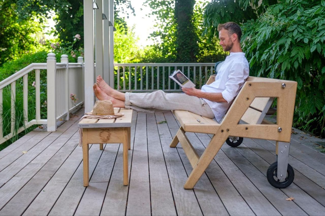 Homme détendu, pieds posés sur un banc d'appoint, en position lounge sur le mobilier b-convivio